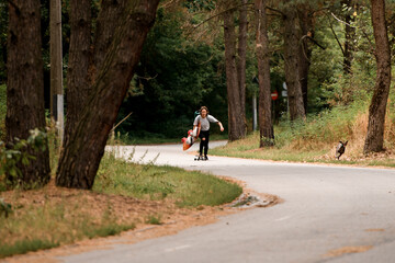 beautiful view of road along which young woman rides on skateboard with wakeboard in her hand