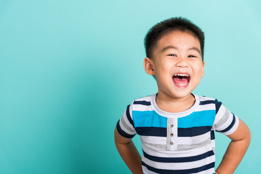 Asian Portrait Of Cute Little Boy Kid Happy Face He Laughing Smiles And Looking To Camera, Studio Shot Isolated On Blue Background