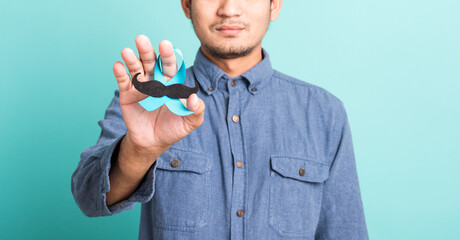 Asian portrait happy handsome man posing he holding a light blue ribbon and mustache, studio shot...