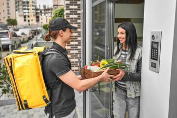 A courier with a backpack and food delivered an online order to the customer's home. The woman...