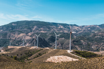 Paisaje de turbinas e&oacute;licas rodeado de monta&ntilde;as