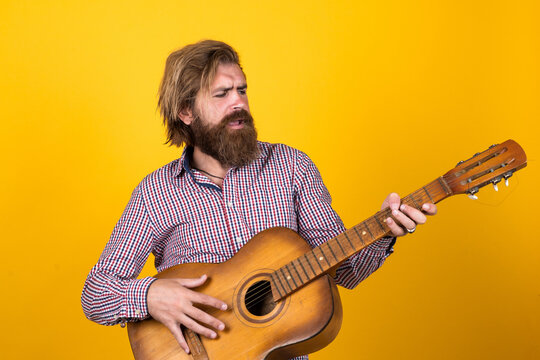 Brutal man. guy with beard and moustache play guitar. bearded man in checkered shirt sing song. music performer musician. musical string instrument. mature charismatic male guitarist