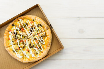 Pizza with chicken, tomatoes, pepper, cheese and sauce in a box. Horizontal orientation, top view, copy space.