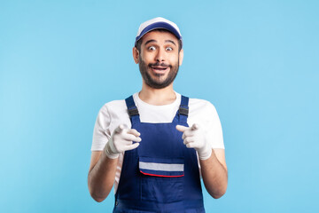 Wow hey you! Amazed crazy handyman in overalls pointing to camera and looking surprised. Profession...