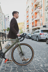 Fototapeta premium Full length shot of a stylish man walking across the road with his bike