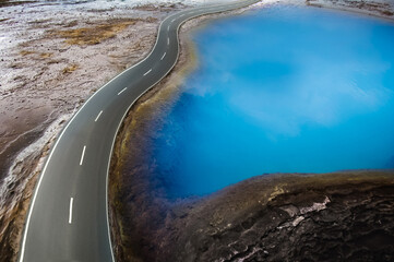 Photo composing illustrationof a winding road that leads past a deep blue shining lake.