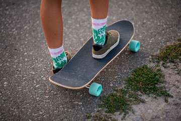Close-up of feet of girl standing with skateboard on asphalt