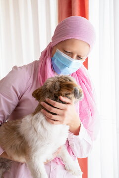 Woman with cancer, pink headscarf and mask hugging her pet