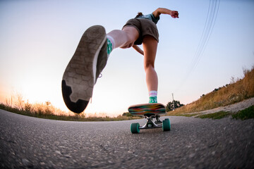 low angle view of young woman riding on skateboard on the asphalt.