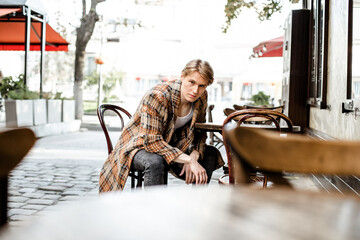 The man is sitting at the table and waiting for a meeting. Tall handsome blond, glance
