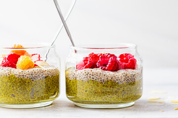 Chia pudding with matcha tea and berries in glass jar, white background. Healthy food concept.