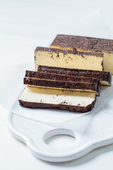 Sliced smoked tofu on white board, white background. Vegan food concept.