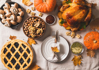 Fall thanksgiving table with roasting chicken or turkey, nuts, pie, pumkins and other food on light