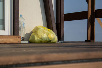 an abandoned yellow garbage bag and a plastic bottle at an empty house on the riverbank. Concept of protection from environmental pollution