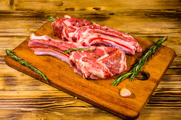 Raw ribeye steak, spices, rosemary and garlic on cutting board