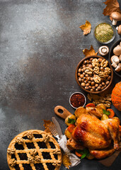 Fall thanksgiving table with roasting chicken or turkey, nuts, pie, pumkins and other food on dark...