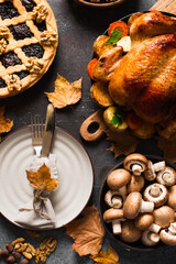 Fall thanksgiving table with roasting chicken or turkey, nuts, pie, pumkins and other food on dark background