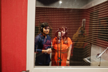 Fototapeta na wymiar Young asian duet singers with microphone recording song in record music studio.