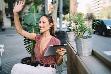 Cheerful woman greeting with hand in cafe