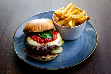 Burger and chips on a blue plate (brown table) view from an angle