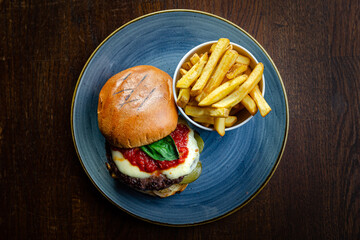 Burger and chips on a blue plate (brown table) top view