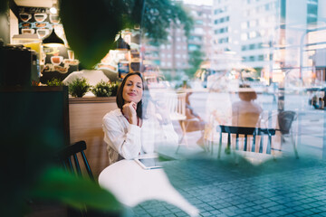 Positive adult lady with tablet sitting in cafe
