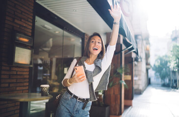 Positive woman greeting with hand in street cafe