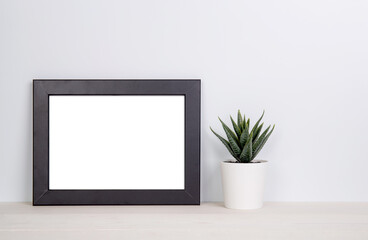 Fototapeta na wymiar Mockup frame and plants in pot on table top at home, mock up poster for presentation on desk, indoor, your design for gallery photo and picture, border template and decoration for advertising.
