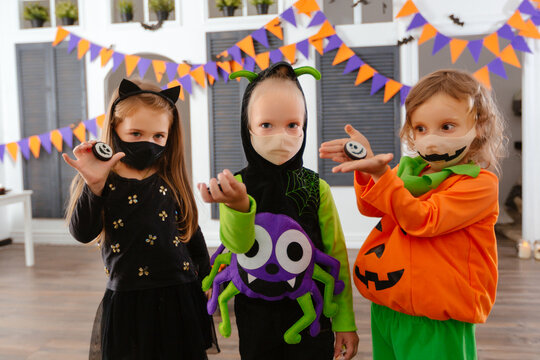 Children in Halloween costumes and with masks on their faces play a trick treat