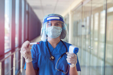 Female doctor using infrared thermometer to check body temperature in clinic