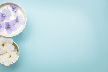 Two mugs filled with flowers on a soft blue background. The concept of big and small togetherness. We are so different, but still we are together. Close up photo