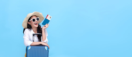Happy young Asian tourist woman holding passport and boarding pass with baggage going to travel on holidays on blue background. - obrazy, fototapety, plakaty