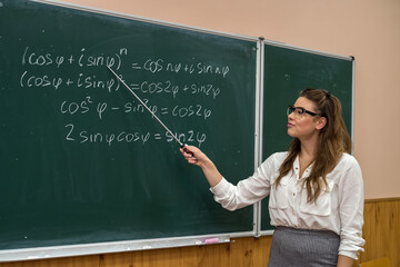 Beautiful caucasian woman teacher standing in classroom near chalkboard