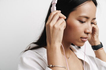 Photo of focused asian woman listening music with headphones