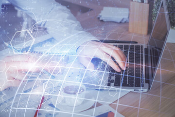 Double exposure of world map hologram with man working on computer on background. Concept of worldwideweb.