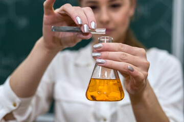 Fototapeta premium The chemistry teacher conducts an experiment with liquids in flask explains to students new topic