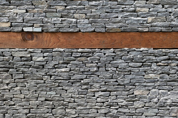 Wooden bands and dry-stacked rubble stone masonry. Abstract background texture.