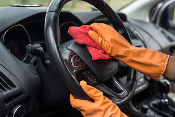 female hand cleaning her car interior from coronavirus and pandemic with disinfectant fluid