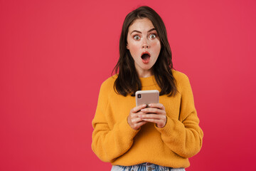 Image of shocked brunette girl posing and using mobile phone