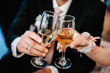 The bride and groom holds a glass of champagne and stand on wedding ceremony. Close up.