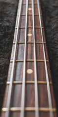 Neck and fingerboard of a jazz bass guitar with black background.