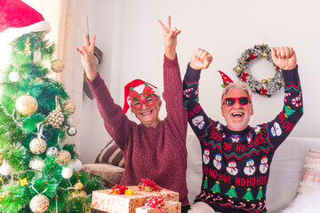 couple of two crazy and funny seniors playing having fun together and celebrating doing a party at home the christmas day before wrap the presents and gifts
