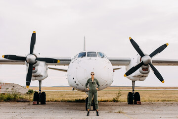 Confident woman pilot wearing uniform, standing in front of an airplane.