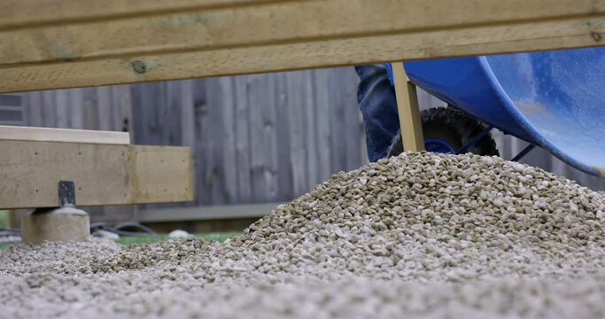 Wheelbarrow dumps out last bit of gravel aggregate - slow motion