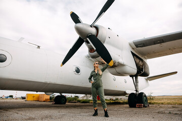 Fototapeta premium Woman pilot wearing uniform, standing in front of an airplane propeller.