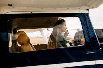 Woman pilot flying an airplane, wearing headset.