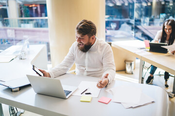 Delighted businessman browsing smartphone in creative workplace