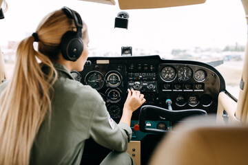 Back view over woman pilot flying an aircraft, wearing headset.