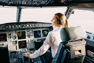 Tuinposter Woman pilot sitting in airplane cockpit, wearing headset. © Bostan Natalia