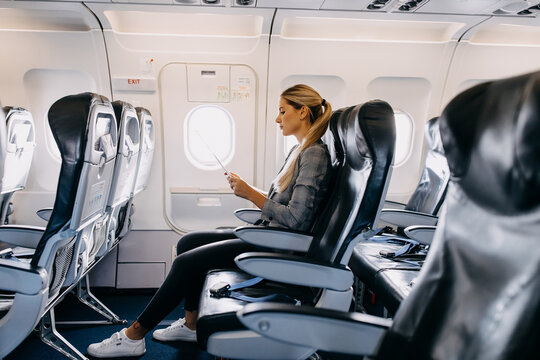 Young Woman Passenger Reading Safety Card Instructions On An Aircraft.